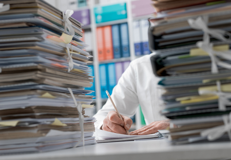 Business executive working in the office and piles of paperwork, he is overloaded with work