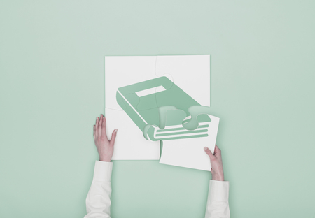 Woman completing a puzzle with a book icon, she is putting the missing piece, education and learning conceptの写真素材