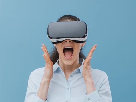 Woman wearing a VR headset and experiencing virtual reality, she is amazed and surprised