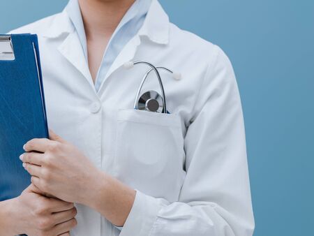 Professional female doctor holding a clipboard and posing, healthcare professionals concept