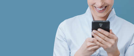 Smiling woman connecting online with her smartphone and chatting on social networks