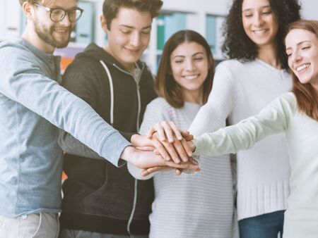 College students and friends stacking hands together and smiling, teamwork and collaboration conceptの写真素材