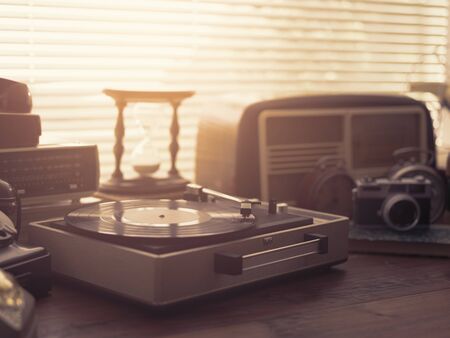 Vintage retro revival objects and appliances assortment on a table, turntable record player on the foregroundの写真素材