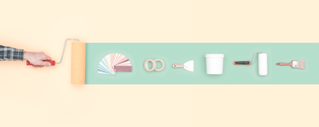 Man painting a stripe using a paint roller and do it yourself tools: decoration, renovation and creativity conceptの写真素材