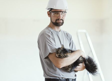 Confident handsome repairman posing and holding a beautiful long hair catの写真素材