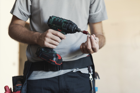 Professional handyman changing a drill bit: home renovation and manual work conceptの写真素材