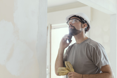 Professional builder with safety helmet having a phone call, home renovation and communication conceptの写真素材