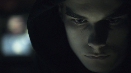 Cool young hacker with hoodie posing in the dark, cyber security and coding concept