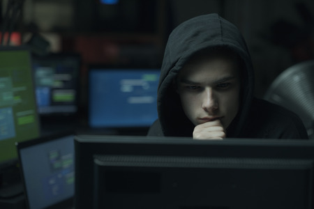 Cool young hacker with hoodie working with computers, cybercrime and data security conceptの写真素材