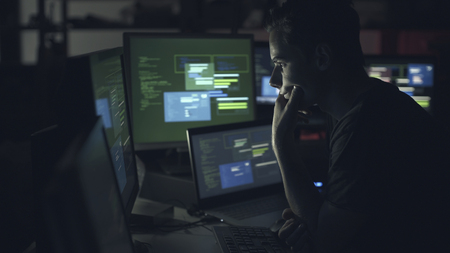 Young computer developer working with computers late at night, coding and hacking conceptの写真素材