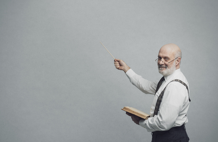 Smiling confident professor teaching and pointing at the blackboard: academic education and learning conceptの写真素材