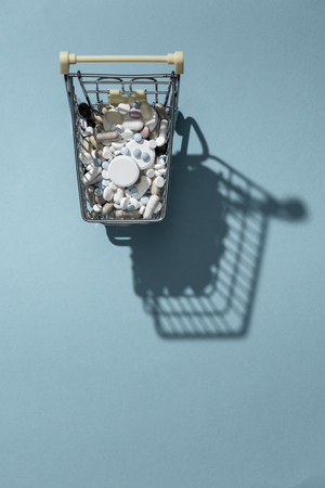 Miniature shopping cart filled with pills, tablets and capsules: pharmacy shopping, medicine and drug abuse conceptの写真素材