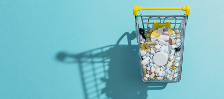 Miniature shopping cart filled with pills, tablets and capsules: pharmacy shopping, medicine and drug abuse conceptの写真素材