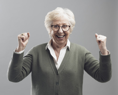Successful senior lady celebrating her victory with raised fists, she is enthusiastic and cheerful