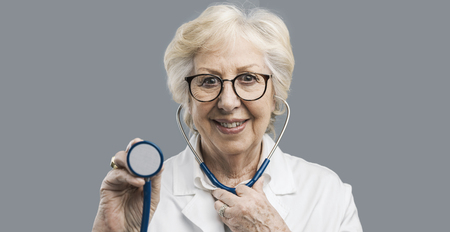 Smiling senior female doctor holding a stethoscope and looking at camera, healthcare and prevention conceptの写真素材