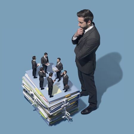 Confident corporate businessman supervising a business team at work, management and human resources conceptの写真素材