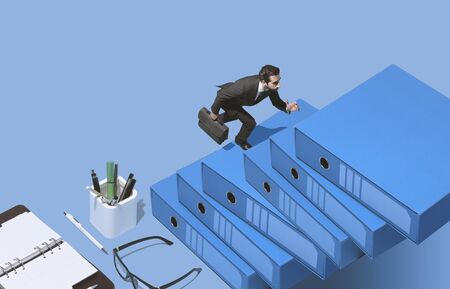 Successful businessman running to reach his goals: he is climbing a pile of ring binders and...