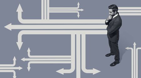 Corporate businessman standing in front of many arrows, he is thinking about business opportunities...
