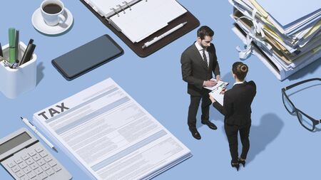 Miniature business people working together on a desktop and tax forms, finance and tax refund conceptの写真素材