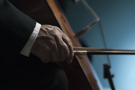 Professional cellist performing on stage, hand close up, classical music concert