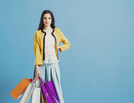 Fashionable young woman holding a lot of shopping bags and posing, style and sales concept