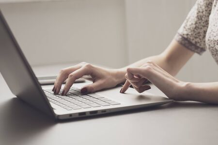 Woman sitting at desk and working with her laptop, hands close up