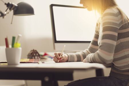 Young creative interior designer working at desk, she is sketching and working on a project