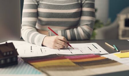 Professional interior designer working at desk and sketching on a house plan, creativity and...