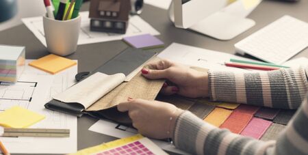 Professional creative decorator working at desk and choosing fabric swatchesの写真素材