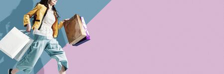 Cheerful stylish woman running to get the latest offers and carrying shopping bags, blank copy spaceの写真素材