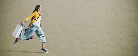Cheerful stylish woman running to get the latest offers and carrying shopping bags, blank copy space