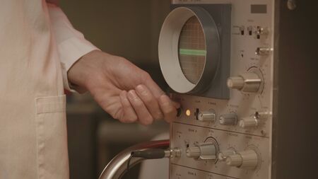 Scientist using an old machine in the laboratory and adjusting knobs, research and science concept