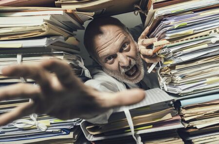 Panicked stressed businessman overloaded with paperwork, he is asking for help and assistance
