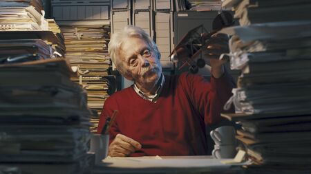 Senior lazy office worker with vintage toy plane: he is playing and having fun instead of workingの写真素材