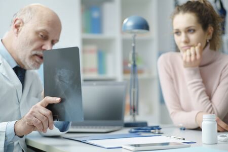 Professional radiologist sitting at desk and checking a patient's x-ray image, diagnosis and healthcare conceptの写真素材