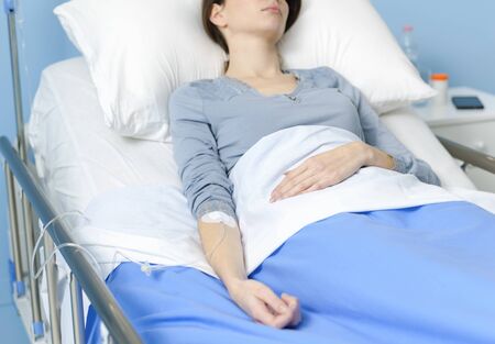 Young female patient lying in bed with IV drip, medicine and treatment concept