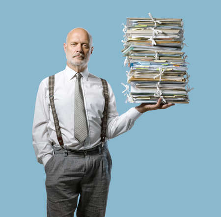 Confident businessman holding a pile of paperwork effortlessly with one hand, easy business administraton conceptの写真素材