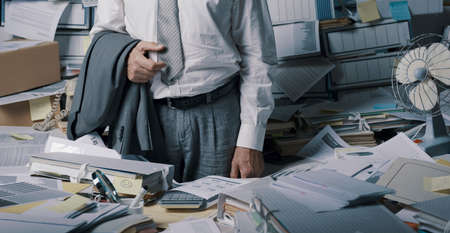 Stressed senior businessman overloaded with paperwork, he is standing, feeling hopeless and exhaustedの写真素材