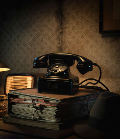 Vintage telephone on a pile of paperwork, film noir style office desktopの写真素材