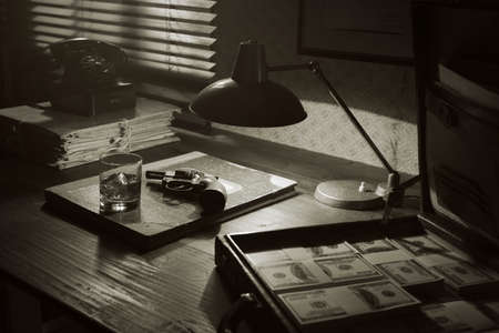 Vintage film noir style desktop with revolver, drink and open briefcase full of cash money: mafia, crime and thriller conceptの写真素材