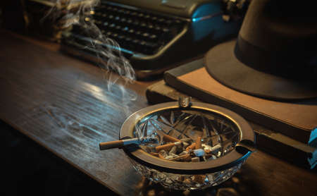 Vintage detective desktop with typewriter, fedora hat and ashtray, film noir styleの写真素材