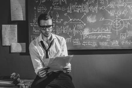 Young researcher studying mathematics in his office, he is checking papers, solving problems and...