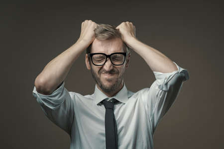 Disappointed businessman with head in hands, he has made a mistake and he is panickingの写真素材