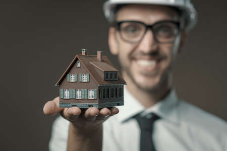 Smiling architect holding a model house, real estate and construction industry conceptの写真素材