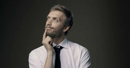 Pensive businessman thinking with hand on chin, problem solving and decisions concept