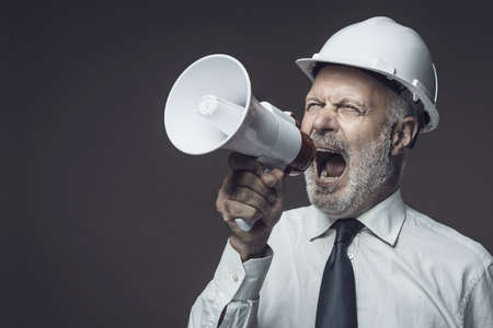 Senior engineer and businessman shouting into a megaphone, marketing and communication conceptの写真素材