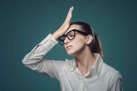Confused businesswoman doing a facepalm gesture, she has made a mistake and feels regretfulの写真素材