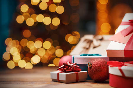 Beautiful Christmas gifts on a table at home and tree with lights in the background, festivity and holiday conceptの写真素材