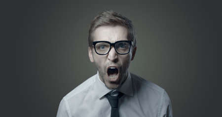 Angry aggressive businessman shouting at camera, he is frustrated and stressed