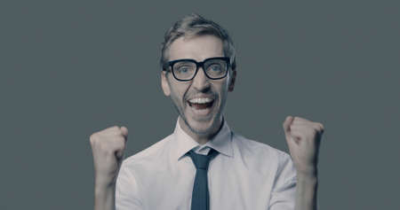 Cheerful happy businessman celebrating with raised fists, achievement and success concept